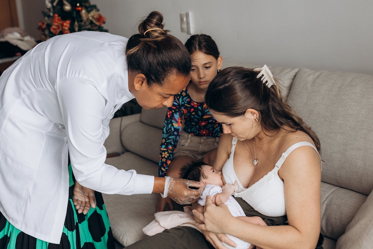 A woman holding a baby while another woman looks on