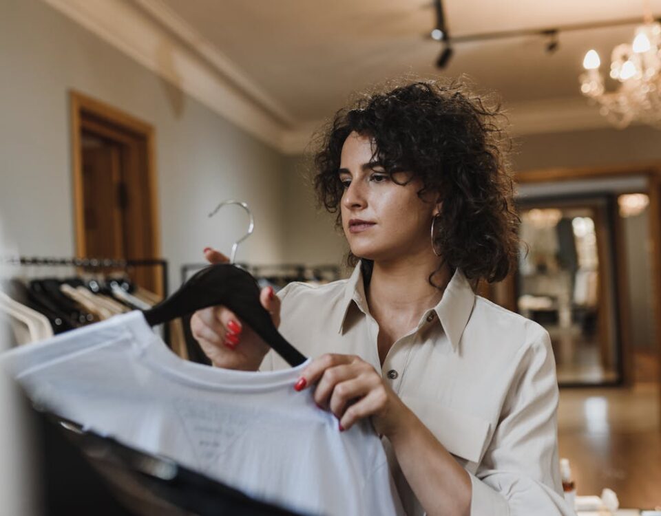 Woman in Beige Long Sleeve Shirt Holding Clothing Hanger