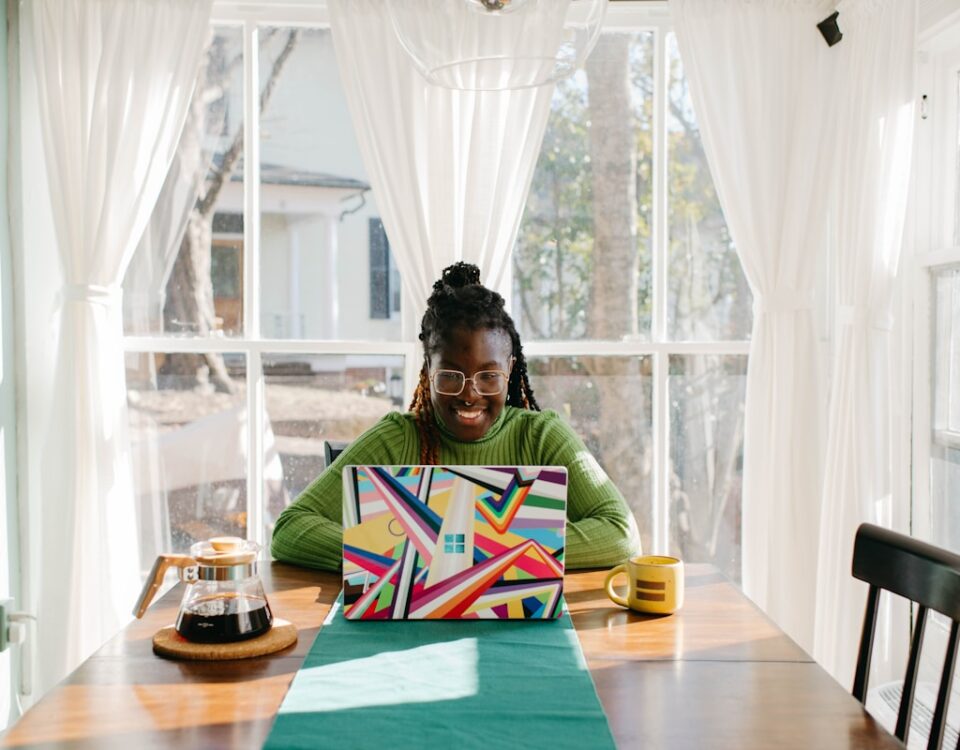 a woman sitting at a table using a laptop computer