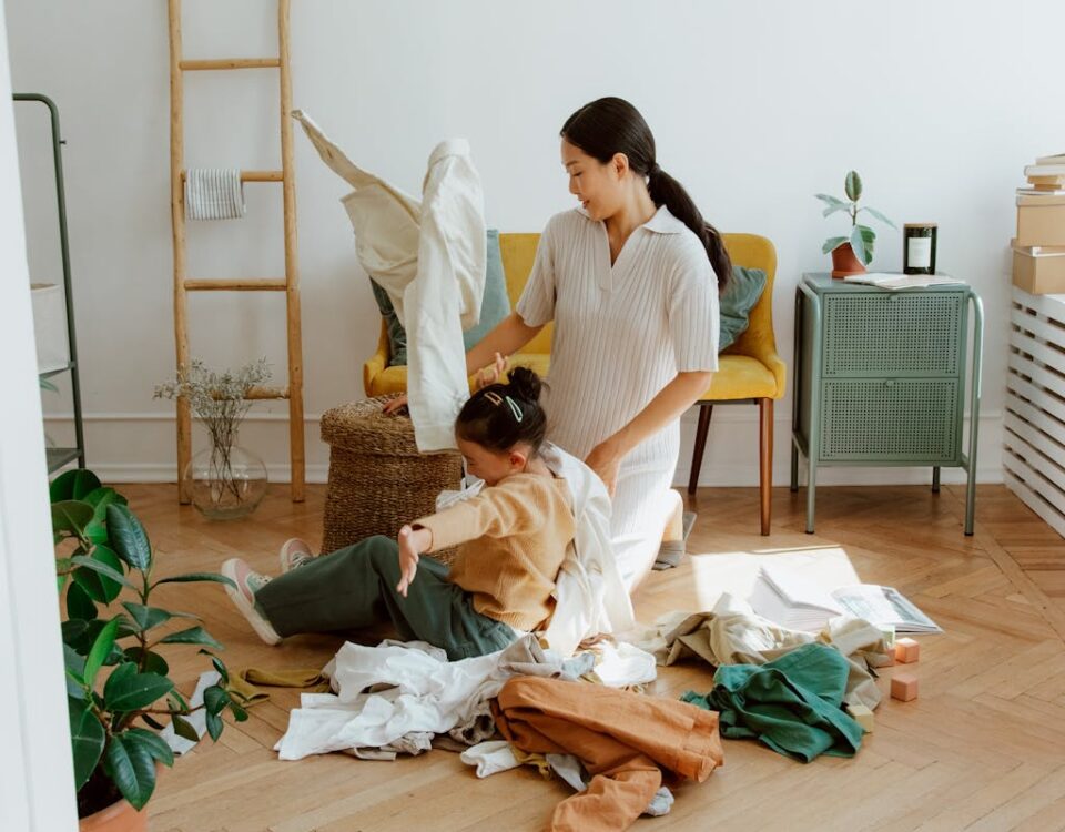 Mother and daughter enjoying quality time organizing clothes in a cozy, sunlit living room.