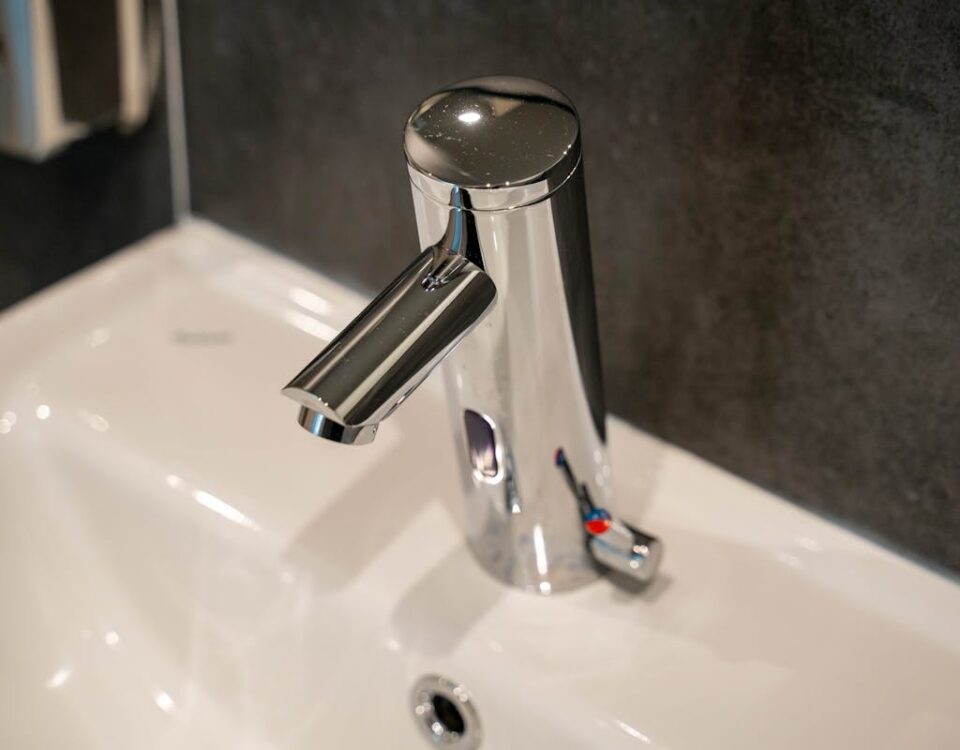 Close-up view of a modern, shiny stainless steel faucet on a ceramic sink.