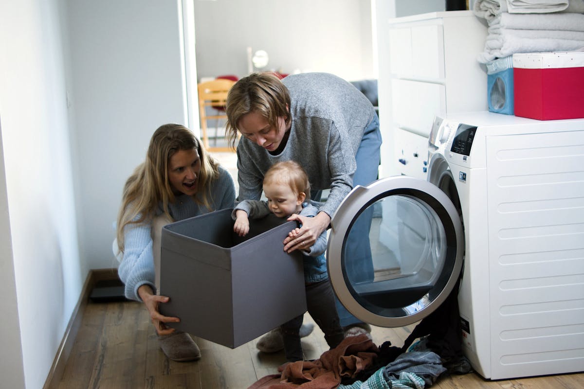 Mother and toddler enjoy playful bonding time while doing laundry at home.