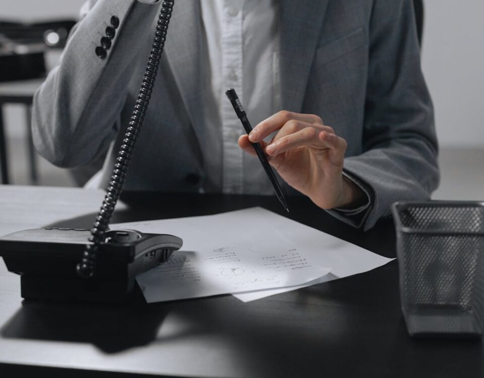 Person Talking on the Telephone While Holding a Pen