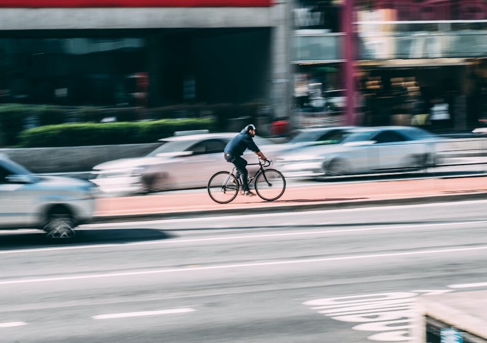 A cyclist rides swiftly through a bustling city street, capturing urban dynamics.