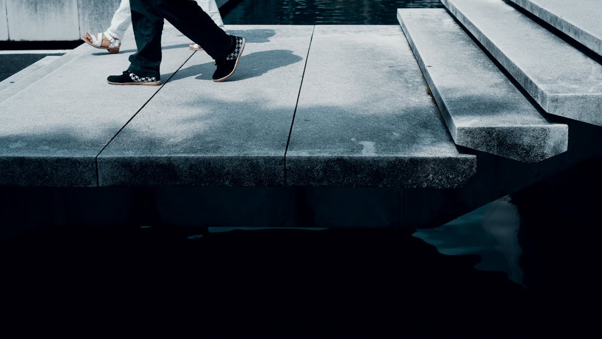 Abstract view of people walking on a modern urban walkway with shadows and steps.