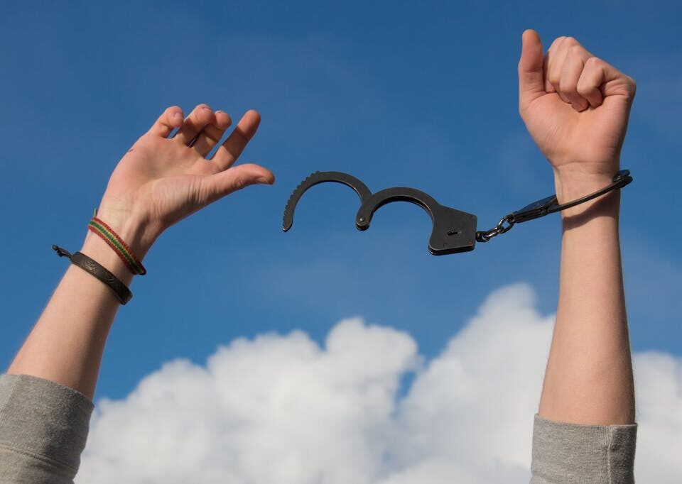 Symbolic image of freedom with open handcuffs against a bright blue sky.