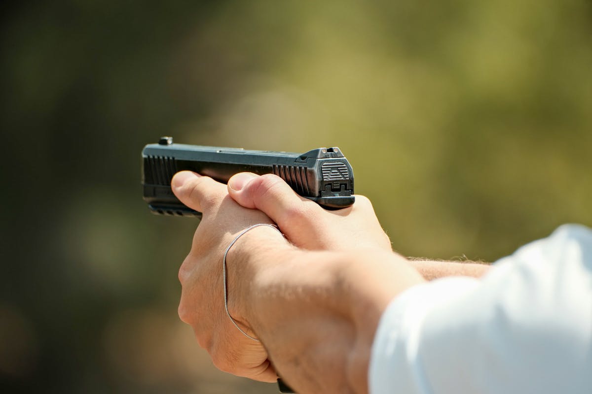 Detailed shot of a person holding a pistol outdoors, focused on safety and precision.