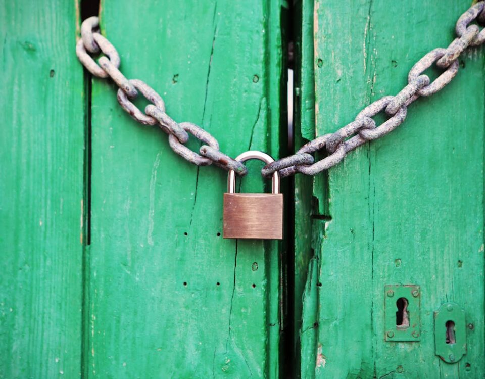 A rustic green wooden door secured with a heavy chain and padlock, symbolizing security.