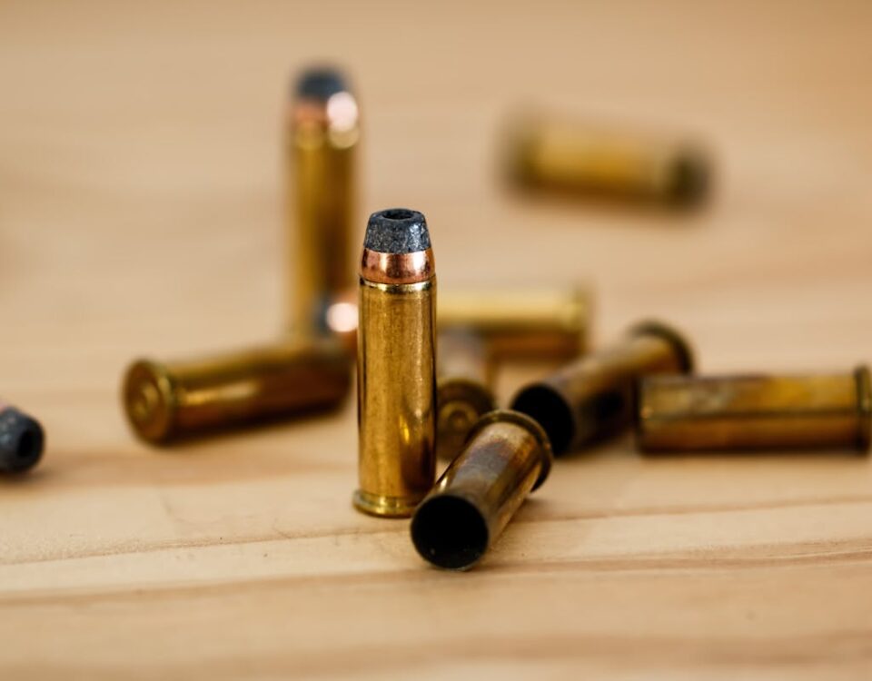 Detailed view of brass bullet shells scattered on a wood background.