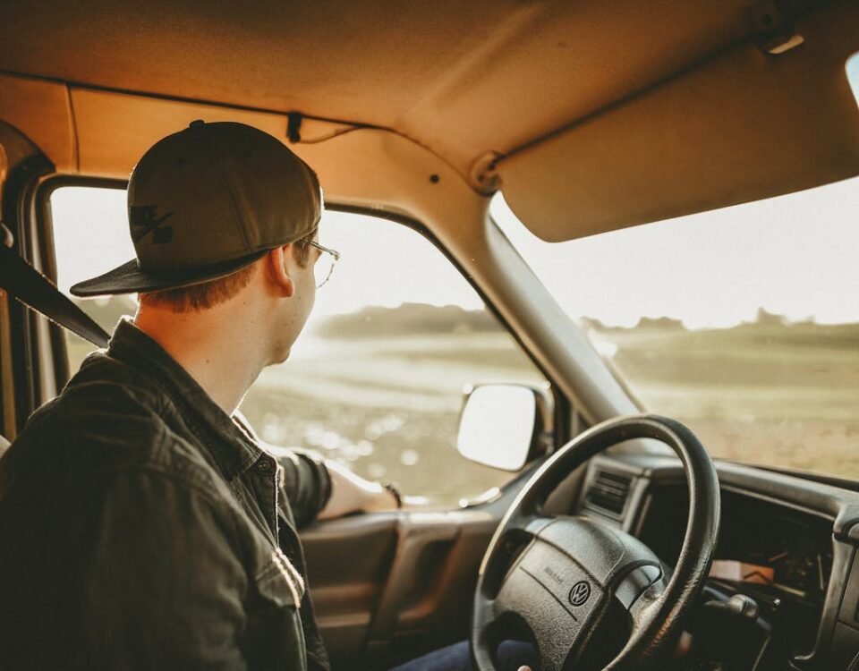 A man enjoys a relaxed drive through the countryside on a sunny day, looking out onto the scenery.