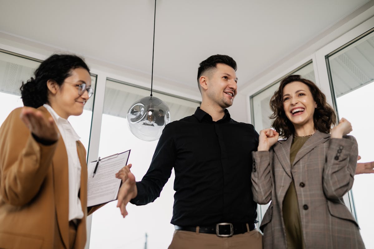 A joyful couple and their realtor celebrate successfully buying a new house indoors.