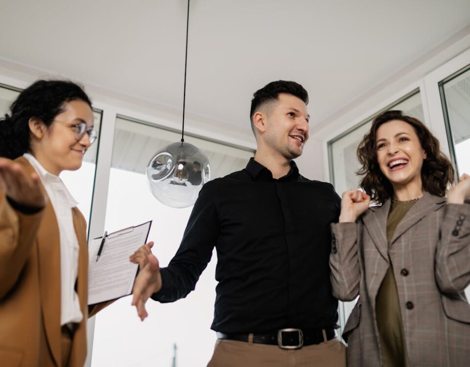 A joyful couple and their realtor celebrate successfully buying a new house indoors.