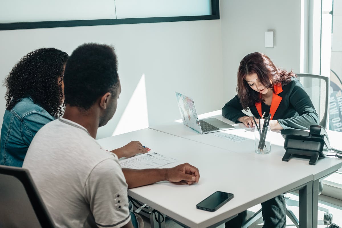 A couple discussing paperwork with an advisor in a modern office setting, showcasing collaboration.