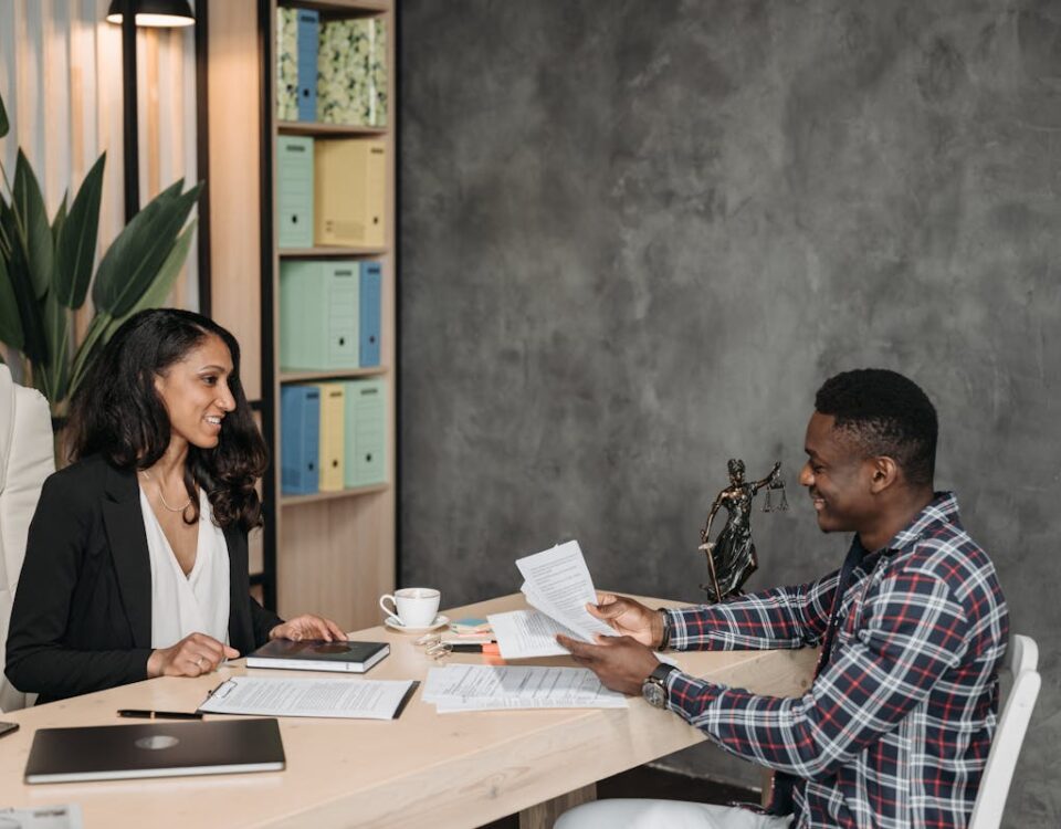 Two professionals having a discussion in a stylish office with paperwork and a laptop.