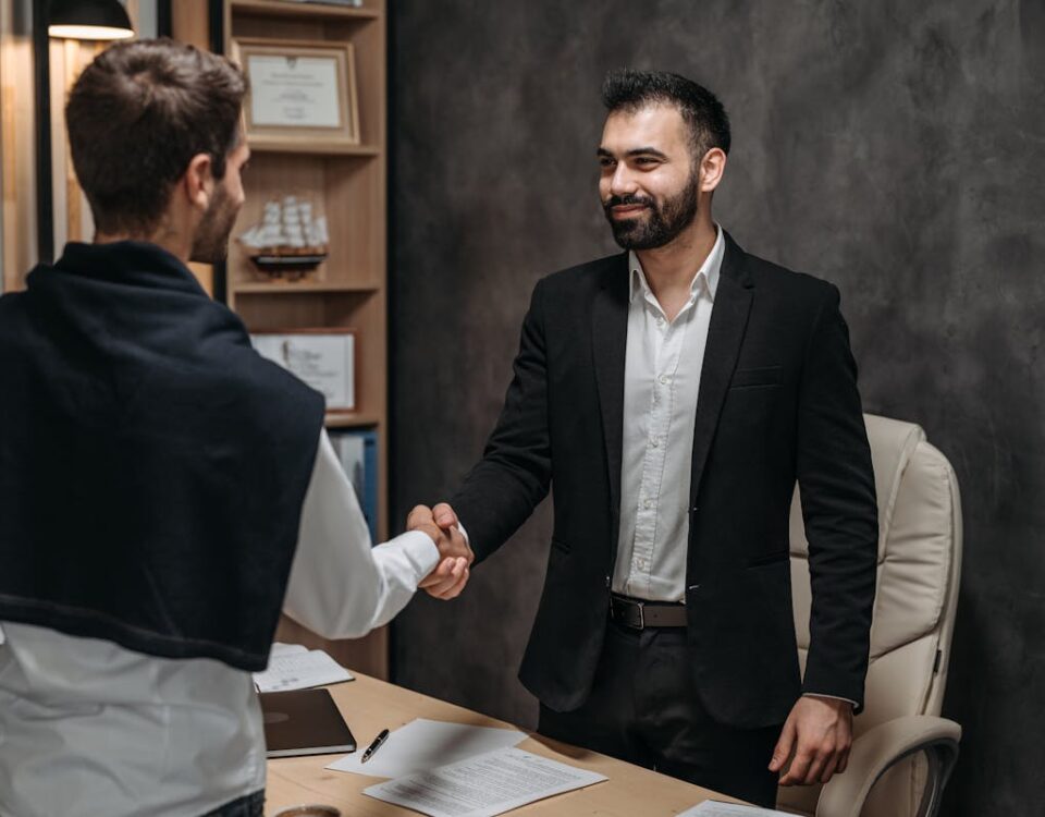 Two businessmen shaking hands in a modern office, sealing a business deal.