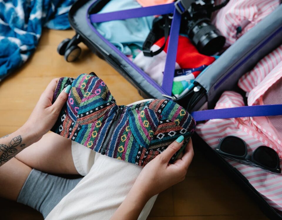 A woman packing a colorful bikini into a suitcase, preparing for her vacation trip.