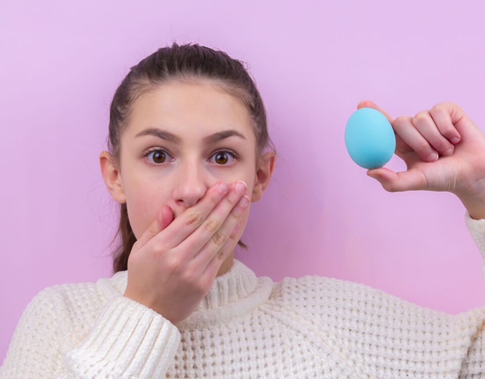 woman in white sweater holding blue balloon