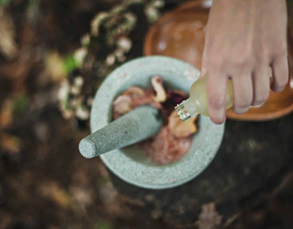 high angle photo of person pouring liquid from bottle inside mortar and pestle