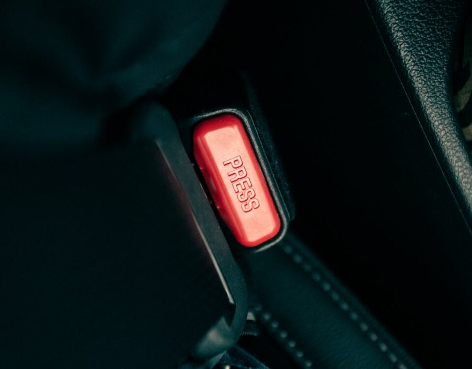 Detailed view of a car seatbelt buckle with a red press button.