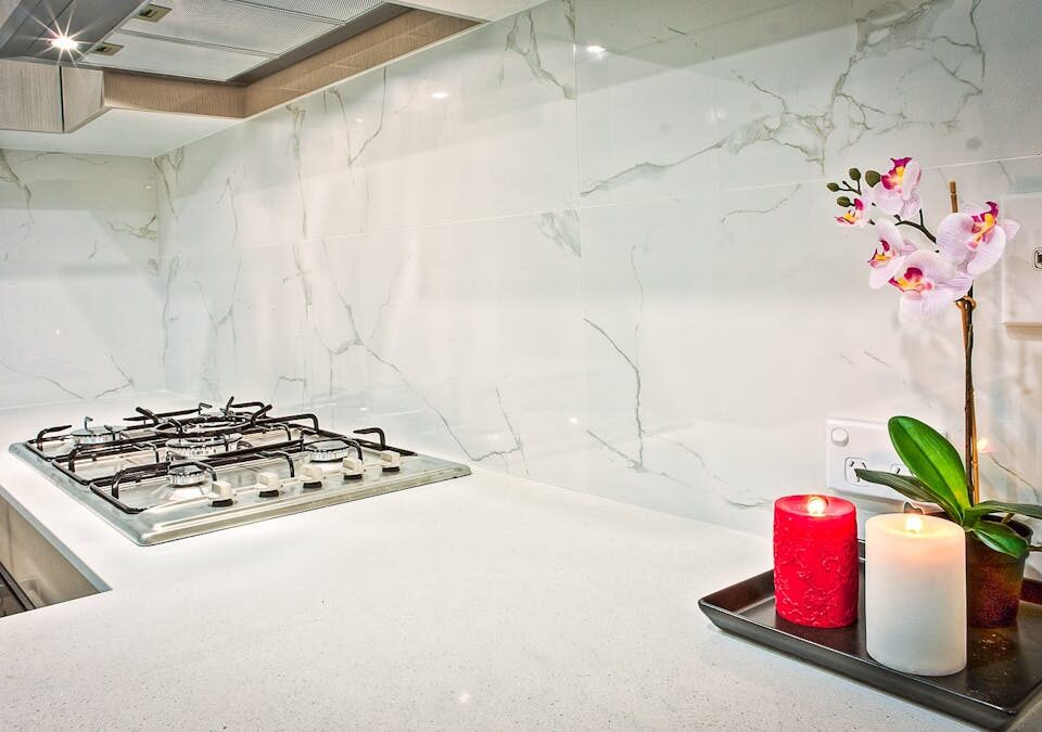 Stylish kitchen interior featuring decorative candles and orchids on a countertop.