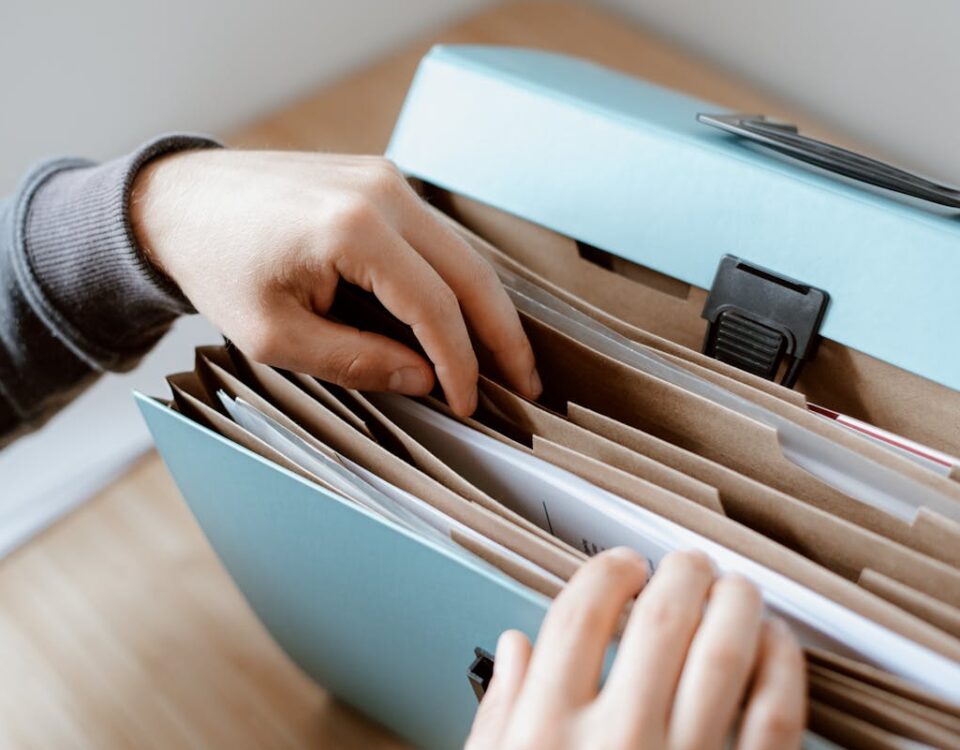 Close-up of hands organizing papers in a blue folder, ideal for business and office concepts.