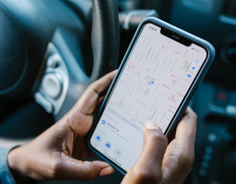 Close-up of hands holding a smartphone with GPS navigation displayed, in a car setting.